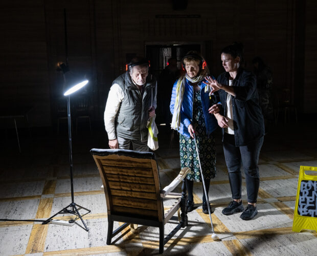Three people standing in dark room
